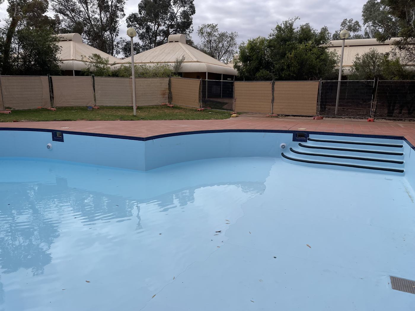 Freeform resort pool with a new light blue membrane, filling with water